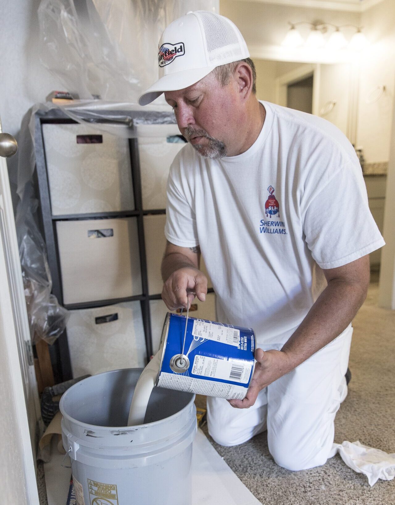 a man pouring paint into a bucket