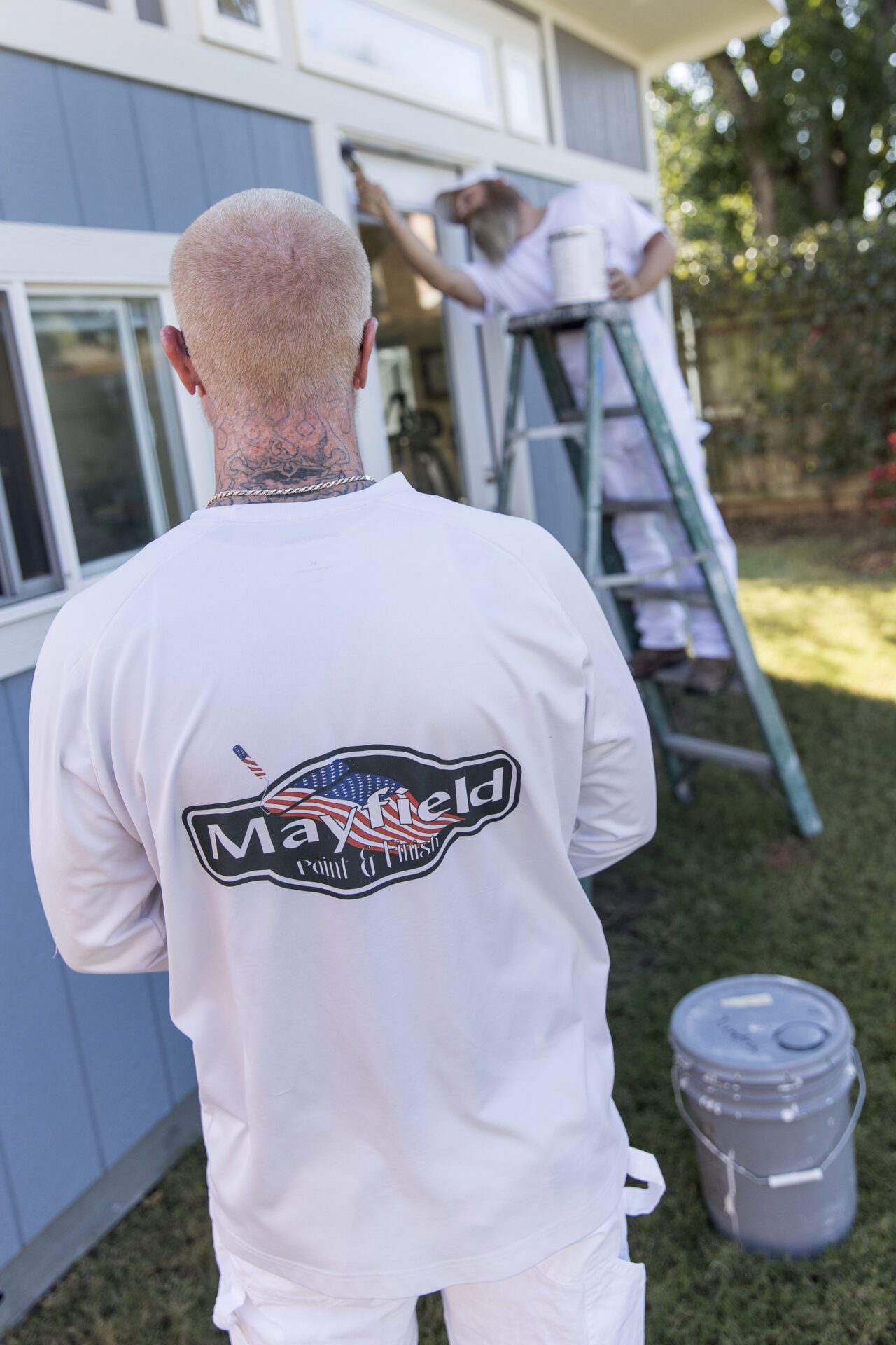 A man with white tshirt print with Mayfield Paint and Finish logo