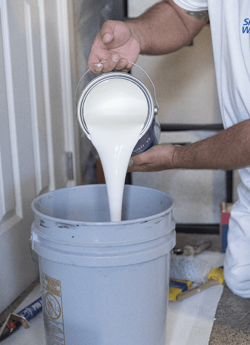 A man pouring paint into a bucket